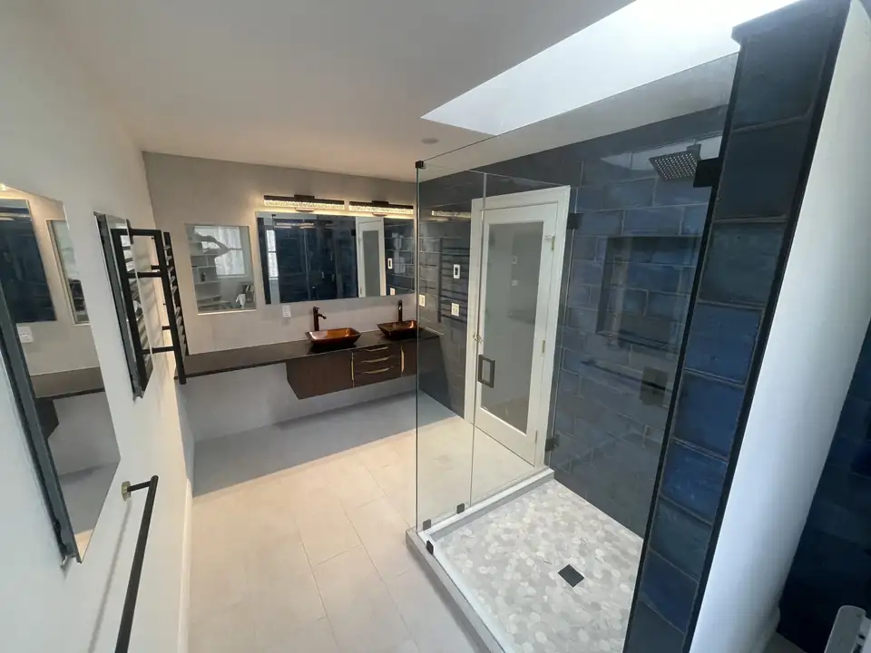 Bathroom remodeling Seekonk MA area: Rehoboth bathroom with a skylight over a frameless glass walk-in shower, navy wall tile and a floating vanity with copper vessel sinks