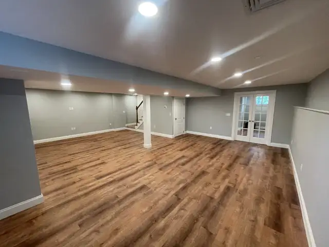 Finished basement in the Seekonk area with wood-look plank flooring, recessed lights and French doors