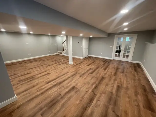 Finished basement with gray walls, wood-look plank flooring, recessed lights and French doors