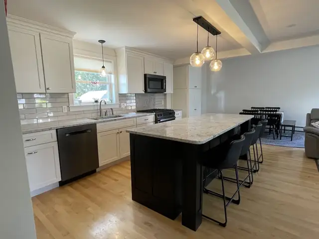 Open kitchen remodel with white shaker cabinets, dark wood island, glass globe pendants and subway tile backsplash