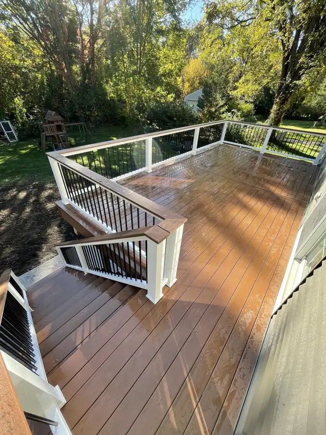 Composite deck with white railings and black balusters overlooking a wooded backyard