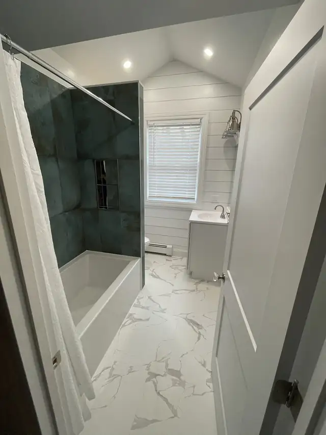 Bathroom remodel with a black double vanity, black framed mirror and black and white mosaic floor